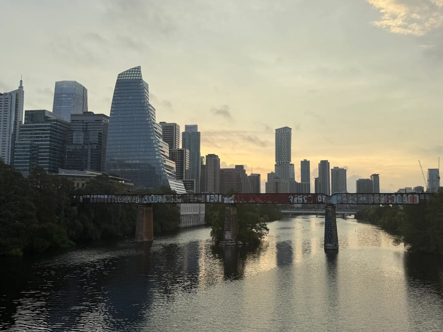 Downtown Austin skyline and a bridge beyond a calm stretch of the river at sunrise